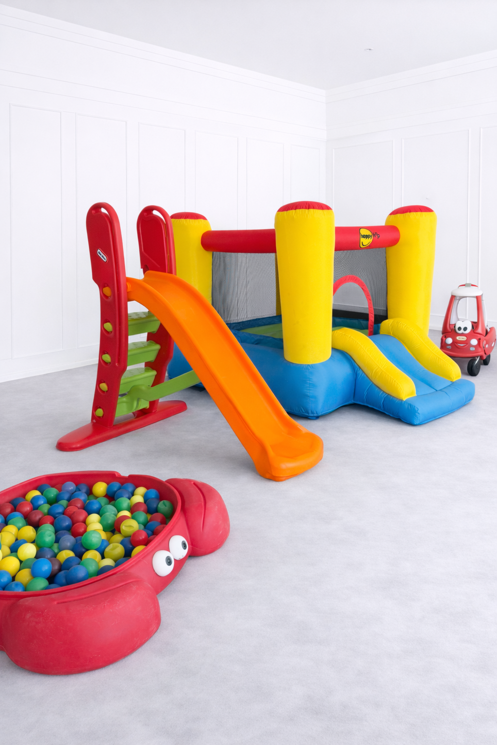 Children's play area with colorful inflatable slide and ball pit on a light gray floor.